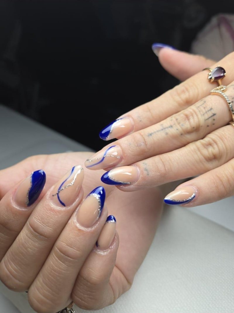 Nail art en azul klein con líneas plateadas sobre base nude