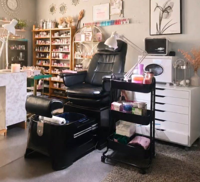 Interior del estudio Únicas: sillón de pedicura, estantes con esmaltes ordenados por color, lámpara de trabajo y carro de materiales